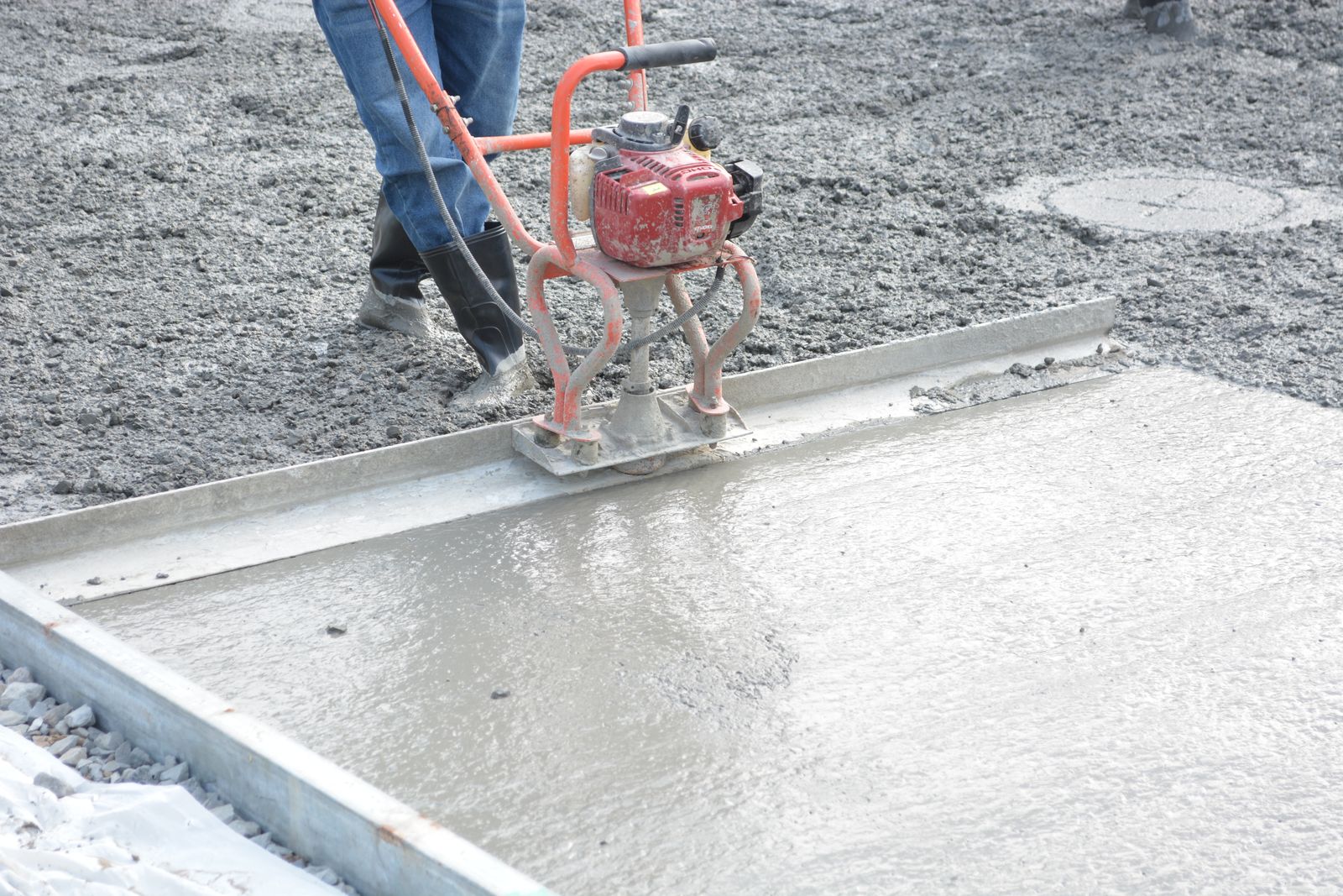 Worker levelling fresh concrete for a new Auckland driveway installation