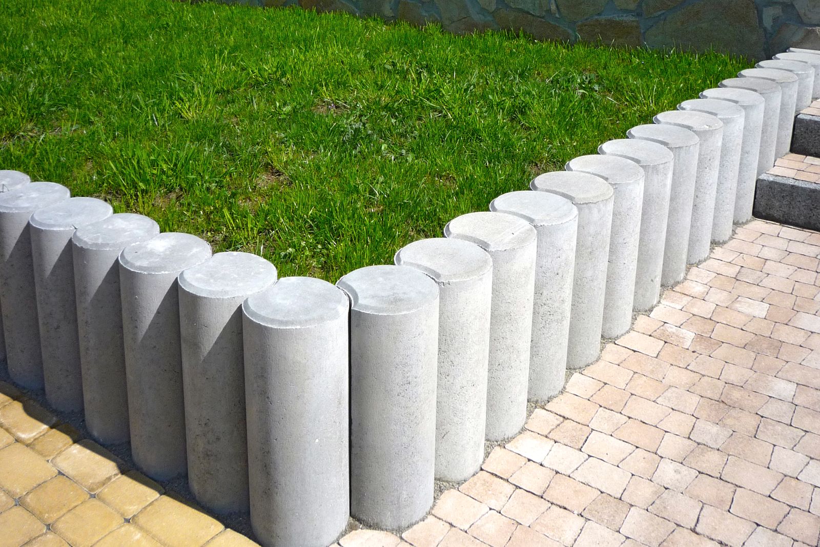 Concrete garden edging blocks beside lawn and paving